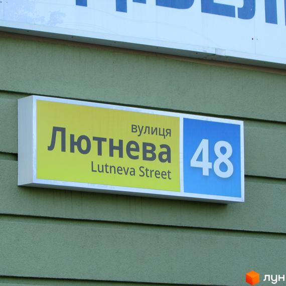 Вуличний знак з назвою вулиці Люнева та номером будинку 48. Зелений фасад будівлі.