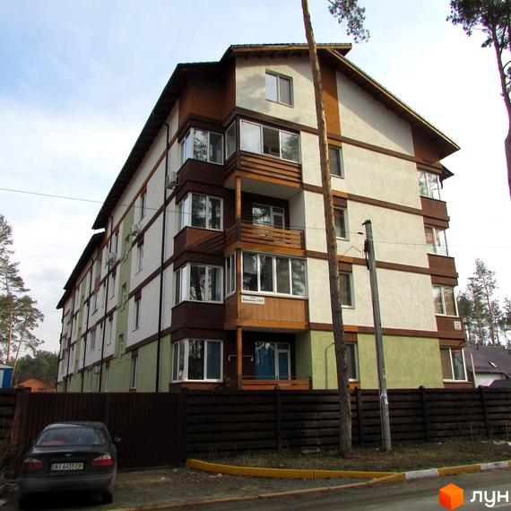 Багатоповерховий будинок Житловий комплекс Європейський з балконами та дерев'яним оздобленням фасаду. На передньому плані парковка та дерев'яний паркан.