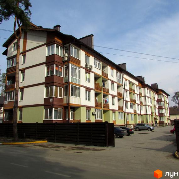 Багатоповерховий будинок житлового комплексу Європейський з паркуванням. Фасад будівлі виконаний у світлих тонах з коричневими та зеленими акцентами.