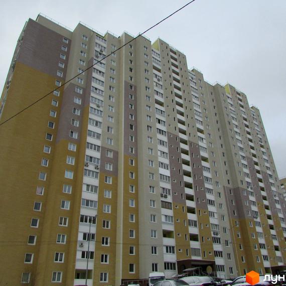 Житловий комплекс Ярославичі з висотним будинком, фасад виконаний у світлих тонах. Прибудинкова територія з автомобілями та зеленими насадженнями.