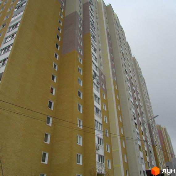 Висотна новобудова ЖК Ярославичі з жовтою цегляною кладкою. На фото зображено фасад житлового будинку з великою кількістю вікон.