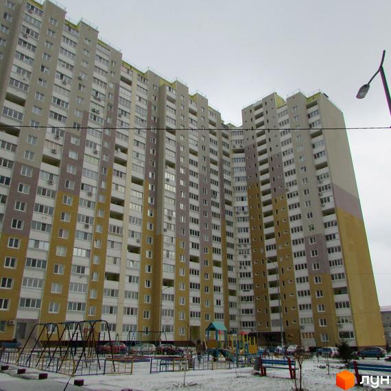 Висотна новобудова ЖК Ярославичі з фасадом у світлих тонах. На прибудинковій території розташований дитячий майданчик та місця для паркування.