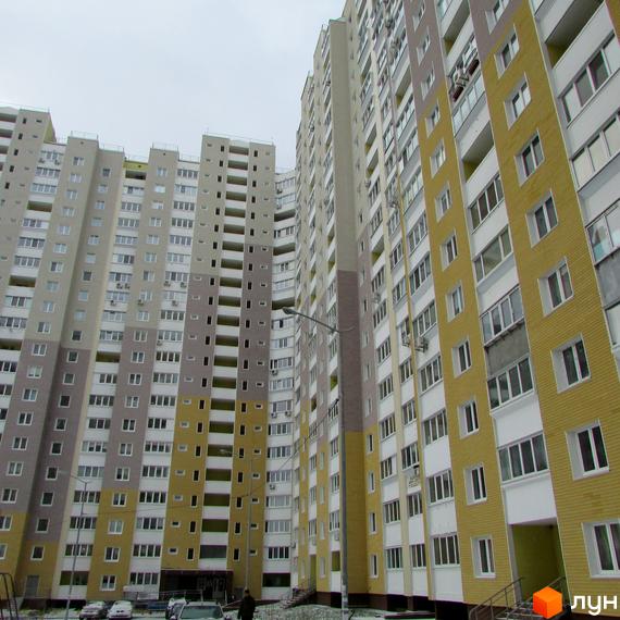 Високі будинки ЖК Ярославичі з великою кількістю вікон. На території комплексу є парковка для автомобілів.