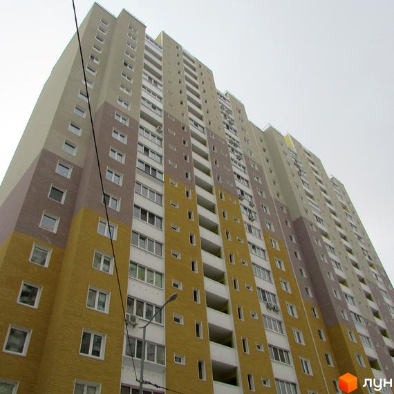 Висотна будівля ЖК Ярославичі з великою кількістю вікон. Фасад будинку виконаний у різних кольорах.