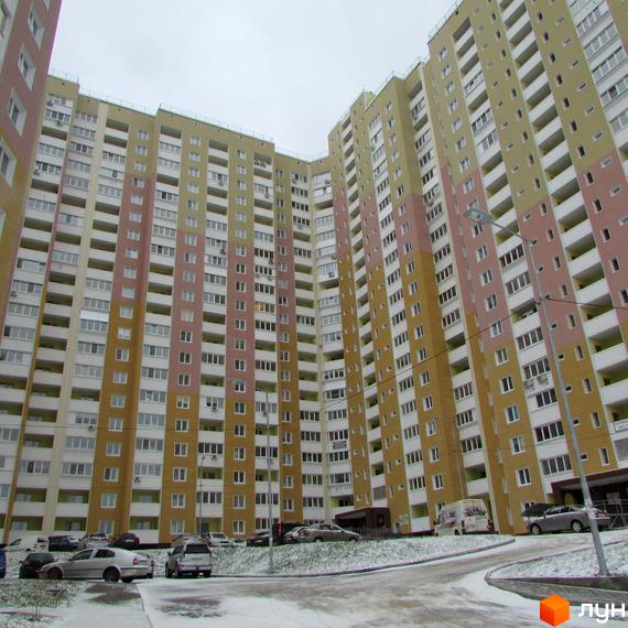 Висотна новобудова ЖК Ярославичі з великою кількістю вікон та балконів. На прибудинковій території видно парковку та невеликий шар снігу.