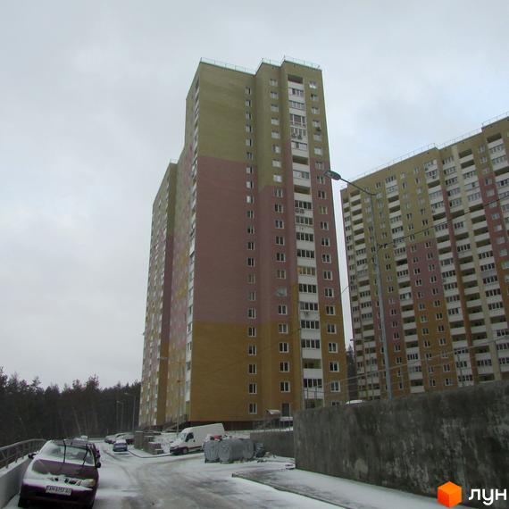 Високі багатоповерхові будинки ЖК Ярославичі на тлі сірого неба. На передньому плані засніжена дорога та припарковані автомобілі.