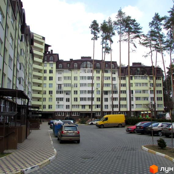 Житловий комплекс Ірпінські Липки. Багатоповерхові будинки світло-зеленого та білого кольору з коричневими дахами. Прибудинкова територія з паркуванням та зеленими насадженнями.