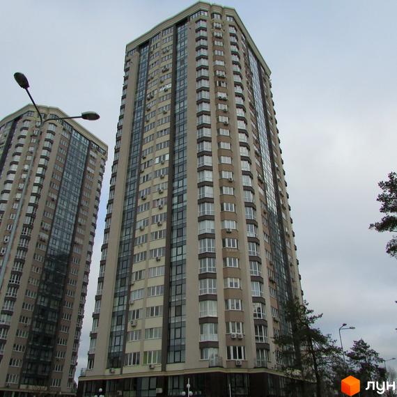 Високі багатоповерхові будинки ЖК Зелений квартал з великою кількістю вікон та кондиціонерів. Навколо будівель видно дерева та вуличне освітлення.