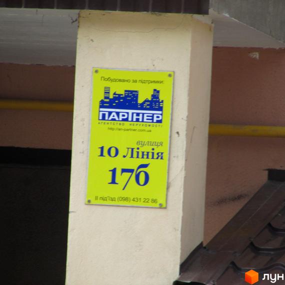 Зовнішній вигляд будівлі за адресою вул. 10 Лінія, 17б. На фасаді розміщено інформаційну табличку з назвою житлового комплексу та контактними даними.
