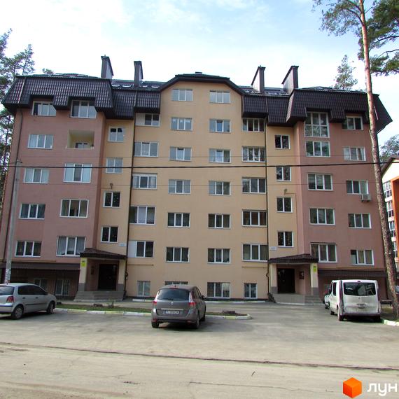 Житловий комплекс на вул. 10 Лінія, 17б. Багатоповерховий будинок з рожевим та бежевим фасадами, темним дахом та прибудинковою територією з автомобілями.