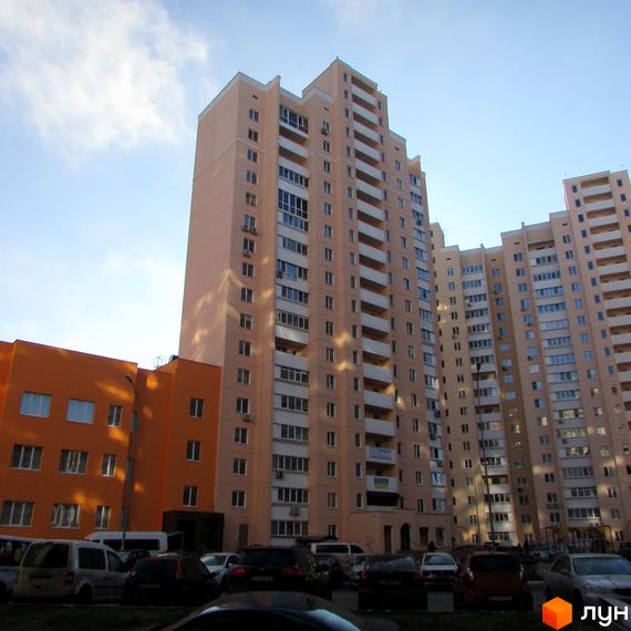 Зовнішній вигляд багатоповерхових житлових будинків на вулиці Грушевського, 21а. Навколо будинків розташовані автомобілі та дерева.