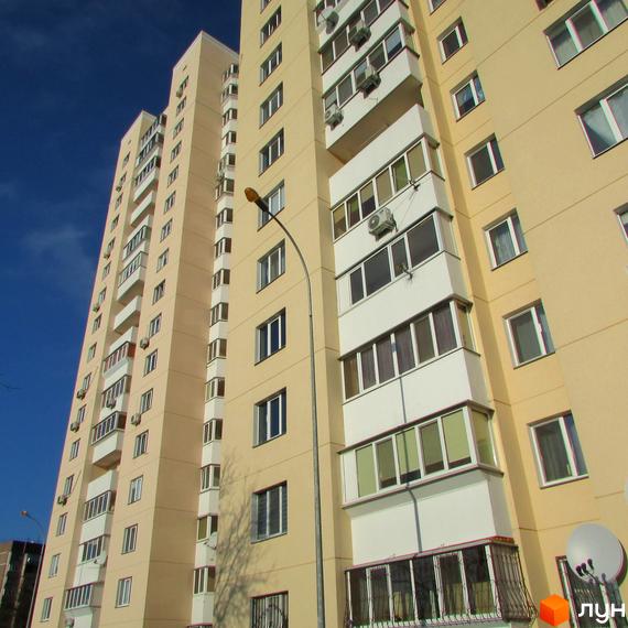 Фасад житлового комплексу на вул. Грушевського, 21а. Багатоповерховий будинок світло-жовтого кольору з численними балконами та кондиціонерами.