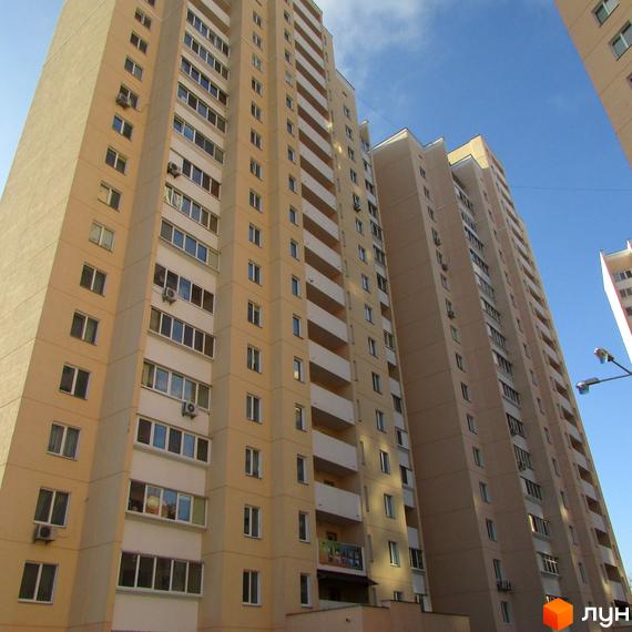 Високоповерховий житловий комплекс на вулиці Грушевського, 21а. Фасад будинку оздоблений світлою штукатуркою, багато вікон та балконів.