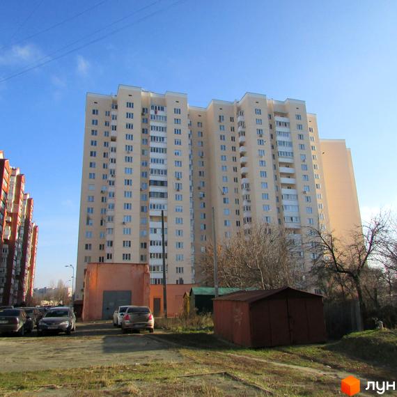 Зовнішній вигляд багатоповерхового житлового будинку на вулиці Грушевського, 21а. На прибудинковій території розташовані гаражі та автомобілі.