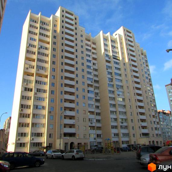 Зовнішній вигляд багатоповерхового житлового комплексу на вулиці Грушевського, 21а. На прибудинковій території видно припарковані автомобілі та дитячий майданчик.