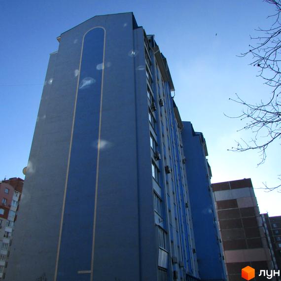 Зовнішній вигляд багатоповерхового житлового комплексу на вул. Грушевського, 17г. Будинок має сіро-блакитний фасад з вертикальною синьою смугою та жовтими вставками.
