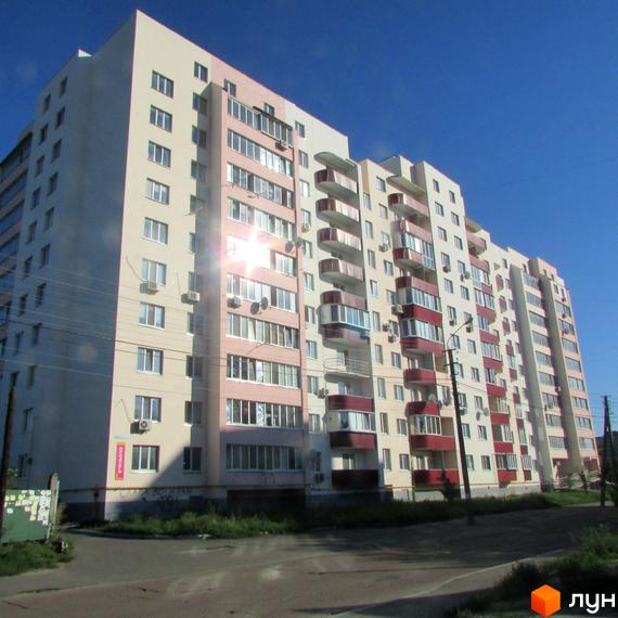 Житловий комплекс Лелека-1 – багатоповерховий будинок з балконами та кондиціонерами на фасаді. Навколо будинку видно зелену зону та дорогу.