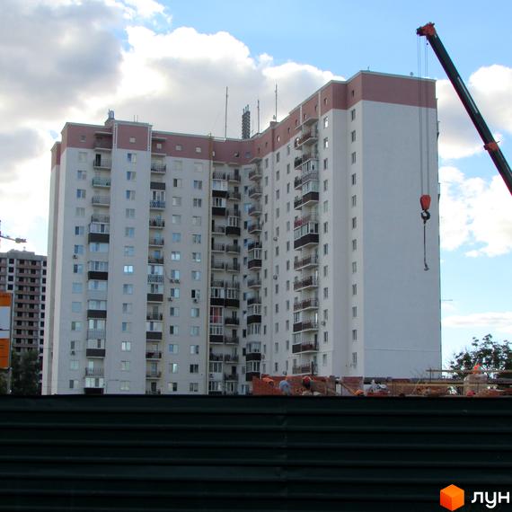 Житловий комплекс Щасливі метри з балконами та сучасним фасадом, прибудинкова територія в процесі облаштування.