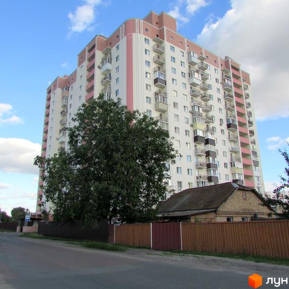 Житловий комплекс Щасливі метри – висотна біла будівля з рожевими елементами та численними балконами. Навколо зелене дерево та паркан.