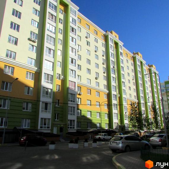 Житловий комплекс Євромісто - багатоповерховий будинок з жовто-зеленими фасадами. Прибудинкова територія з парковкою та зеленими насадженнями.