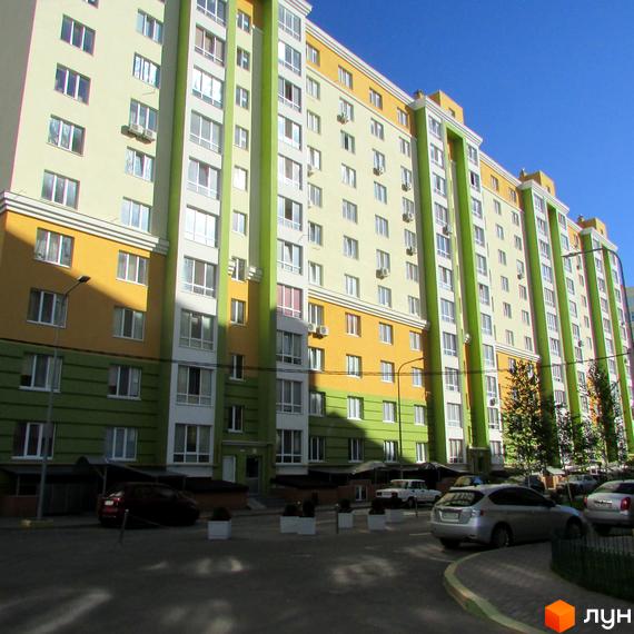 Житловий комплекс Евромісто – багатоповерховий будинок з жовто-зеленим фасадом та великою кількістю вікон. На прибудинковій території розташовані автомобілі та зелені насадження.