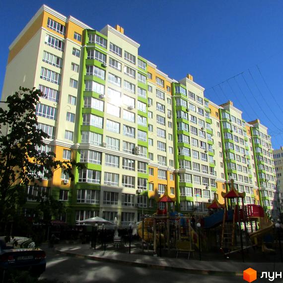 Житловий комплекс Евромісто: багатоповерховий будинок з яскравим фасадом у жовто-зелених тонах та дитячим майданчиком на прибудинковій території.