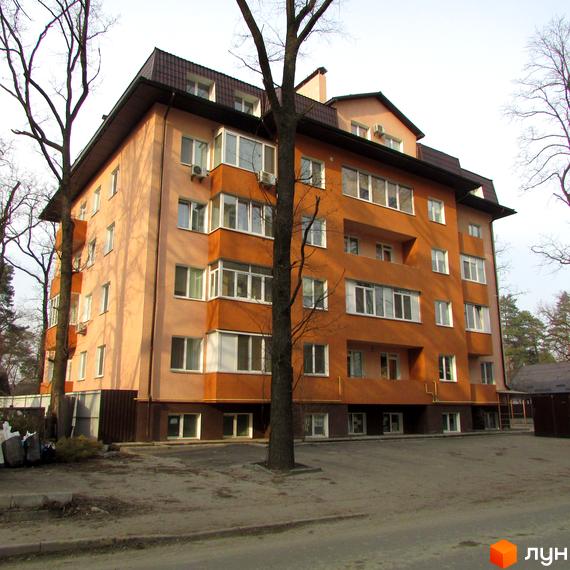 Житловий комплекс вул. Українська, 85в. Багатоповерховий будинок з оранжевим фасадом та балконами, розташований біля дерев. Прибудинкова територія з дорогою та парканом.