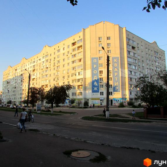 Житловий комплекс на вул. Головатого, 20, з великими вікнами та прибудинковою територією, де гуляють люди.