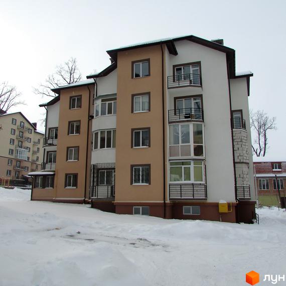 Житловий комплекс Джерело – зовнішній вигляд багатоповерхового будинку з балконами та вікнами на тлі зимового пейзажу. Навколо будинку засніжена територія.