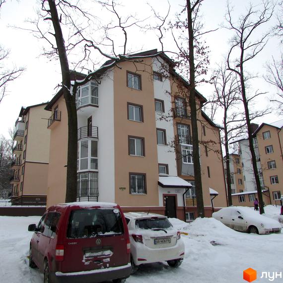 Житловий комплекс Джерело у зимовий період. Багатоповерхові будинки з бежевим та білим фасадом, балконами та вікнами. Прибудинкова територія вкрита снігом, стоять автомобілі.