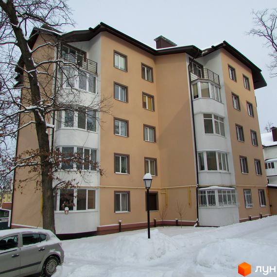 Зовнішній вигляд багатоповерхового будинку ЖК Джерело взимку. Навколо будинку засніжена територія з деревами та автомобілем.