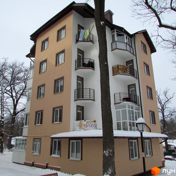 Зовнішній вигляд житлового комплексу ЖК Джерело взимку. Будинок має світло-бежевий та білий фасади, балкони з чорними огорожами. Навколо будинку дерева та засніжена територія.