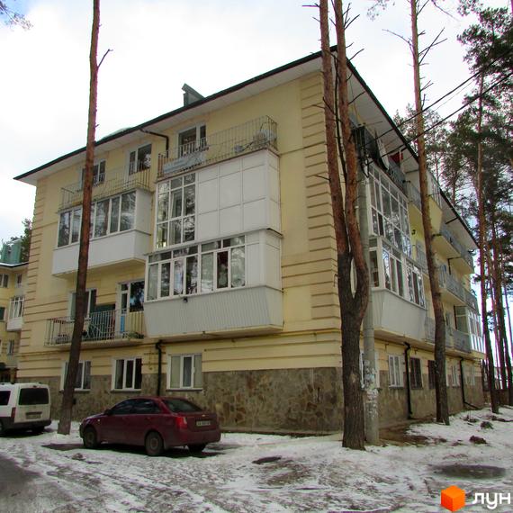 Житловий комплекс на вул. Рильського, 7, з балконами та прибудинковою територією, оточений соснами.