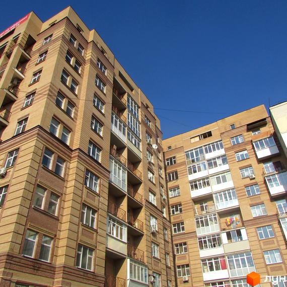 Житловий комплекс на вул. Шевченка, 4, з фасадом з цегли та великими вікнами. Прибудинкова територія з зеленими насадженнями.