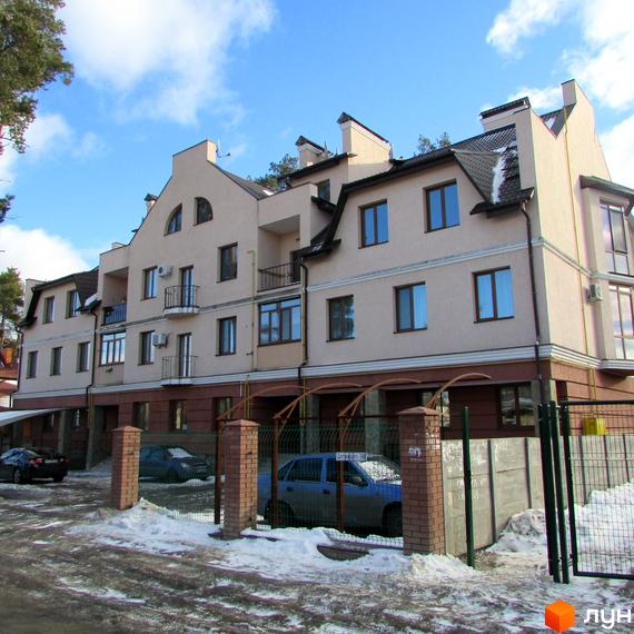 Житловий комплекс на вул. Достоєвського, 39 з фасадом світлого кольору та балконами. Прибудинкова територія з паркувальними місцями та засніженим двором.