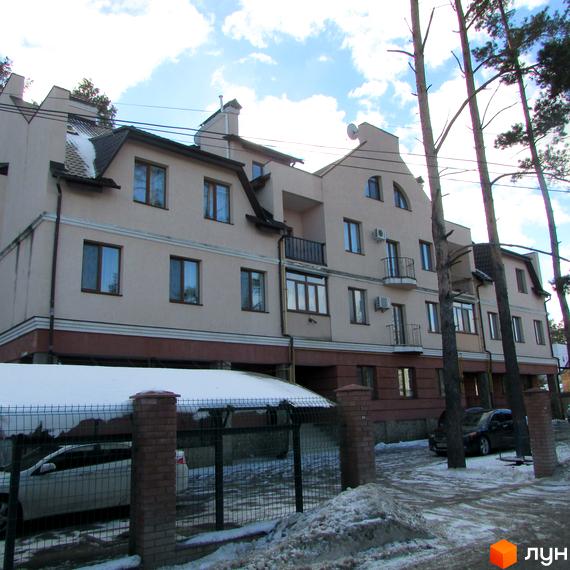 Житловий комплекс на вул. Достоєвського, 39 з фасадом з вікнами та балконами. Прибудинкова територія з паркувальними місцями та зеленими насадженнями.