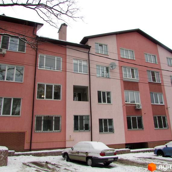 Багатоповерховий житловий будинок за адресою вул. Виговського (Суворова), 5а, пофарбований у рожево-бежеві відтінки. Прибудинкова територія вкрита снігом.