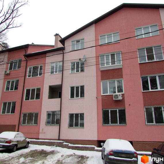 Житловий комплекс на вул. Виговського, 5а, з фасадом в світло-рожевих тонах та великими вікнами. Прибудинкова територія з автомобілями на снігу.