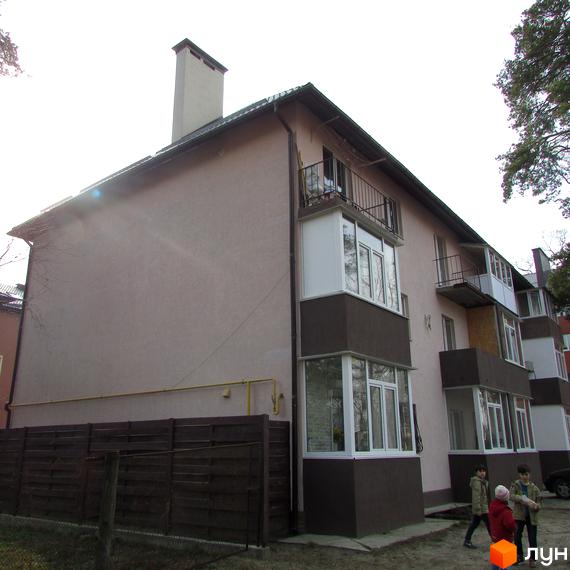 Фасад житлового будинку на вул. Варшавська (Радянська), 95 світло-коричневого кольору з темними балконами. Поруч дерев'яний паркан.