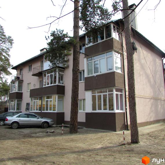 Житловий комплекс на вул. Варшавська, 95, з прозорими балконами та прибудинковою територією з автомобілями і деревами.