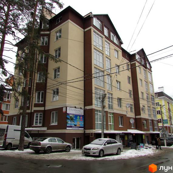 Житловий комплекс на вул. Пушкінська, 62е, з фасадом у світлих тонах та великими вікнами. Прибудинкова територія з автомобілями та снігом.