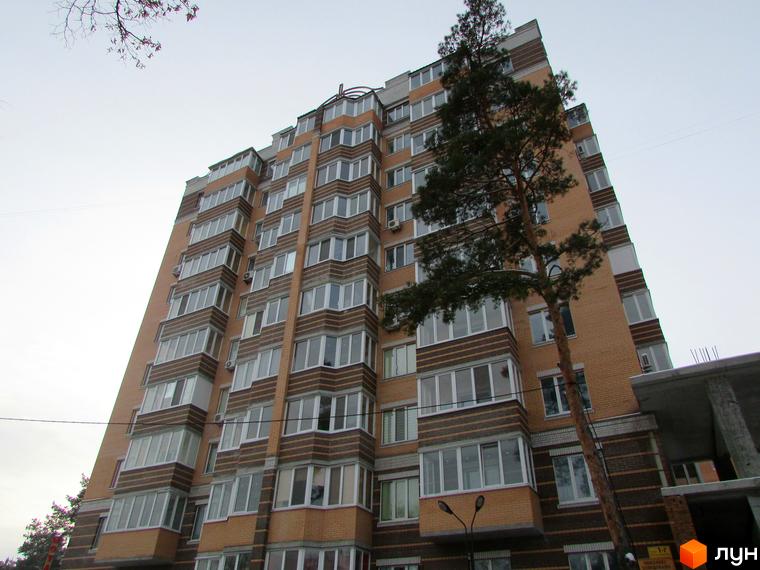 Житловий комплекс Янтарний з багатоповерховим будинком, оточеним зеленими деревами та облаштованою територією.