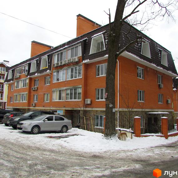 Житловий комплекс на вул. Лермонтова, 6, з червоною цеглою та великими вікнами. Прибудинкова територія з автомобілями та зеленими насадженнями.