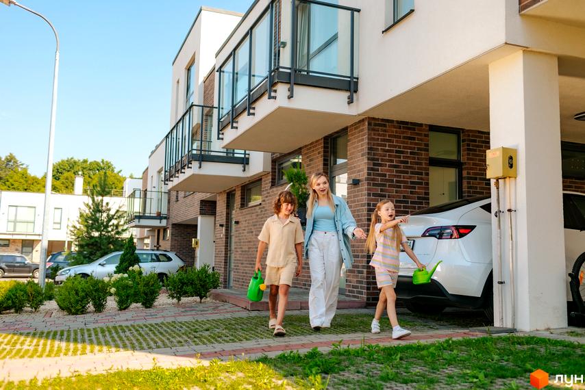 Котеджне містечко Липові Роси: сучасні будинки з цегляним оздобленням та скляними балконами. Прибудинкова територія з доглянутими кущами та доріжками.