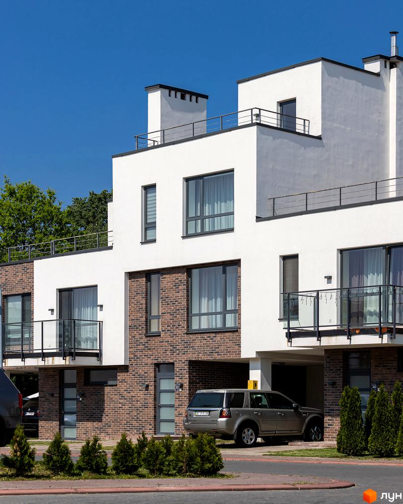 Котеджне містечко КМ Липові Роси: сучасна архітектура з цегляними фасадами та великими вікнами. Прибудинкова територія з зеленими насадженнями та автомобілями.