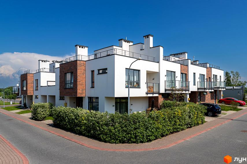 Котеджне містечко КМ Липові Роси – сучасні таунхауси з цегляними фасадами та великими вікнами. Озеленена прибудинкова територія з доглянутими кущами та доріжками.