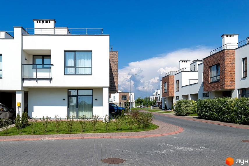 Котеджне містечко Липові Роси: білі фасади будинків з цегляними вставками та зелені насадження вздовж дороги. Огляд території новобудови.