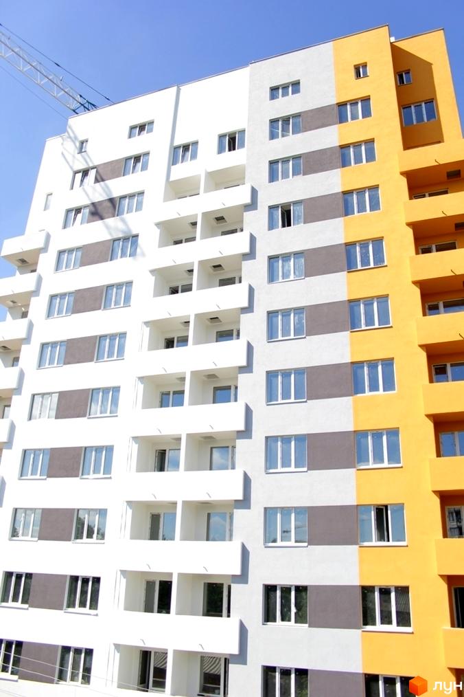 Новобудова ЖК Щасливий у Вишневому. Багатоповерховий будинок з білими, сірими та жовтими фасадами, балконами та численними вікнами.