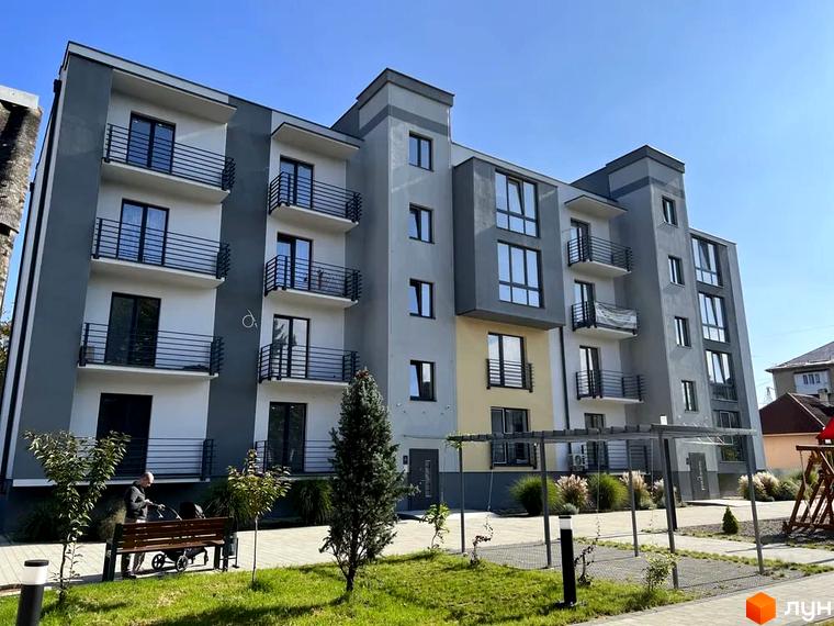 Зовнішній вигляд житлового комплексу Сучасний з балконами та вікнами, прибудинкова територія з лавкою та деревами.