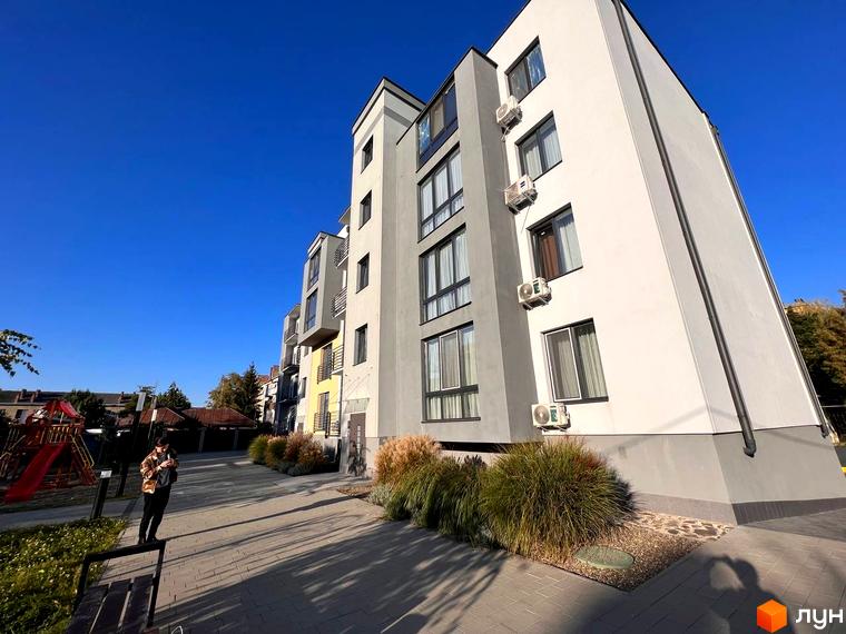 Зовнішній вигляд новобудови ЖК Сучасний з кондиціонерами на фасаді та прибудинковою територією з дитячим майданчиком. Сучасний житловий комплекс з елегантною архітектурою.